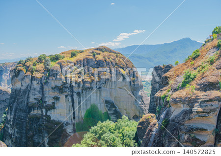 Breathtaking wide view of the ancient Varlaam monastery complex built on a steep cliff in Meteora, featuring iconic red tile roofs and spectacular mountain scenery Breathtaking wide view of the ancient Varlaam monastery complex built on a steep cliff in Meteora, featuring iconic red tile roofs and spectacular mountain scenery 140572825