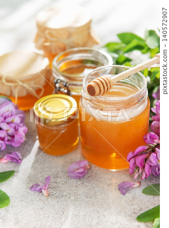 Honey jars with acacia flowers and wooden dipper Honey jars with acacia flowers and wooden dipper 140572907