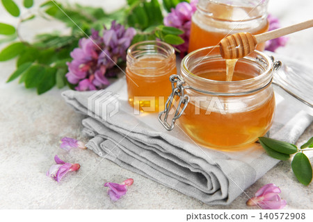 Honey in jars with dipper and acacia flowers Honey in jars with dipper and acacia flowers 140572908