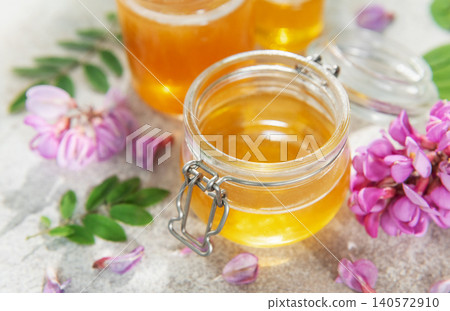 Acacia honey in glass jar surrounded by flowers Acacia honey in glass jar surrounded by flowers 140572910