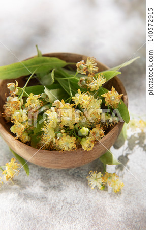 Linden flowers blooming inside wooden bowl for herbal tea Linden flowers blooming inside wooden bowl for herbal tea 140572915