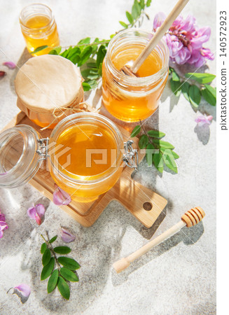 Golden acacia honey in jars with dipper, flowers Golden acacia honey in jars with dipper, flowers 140572923