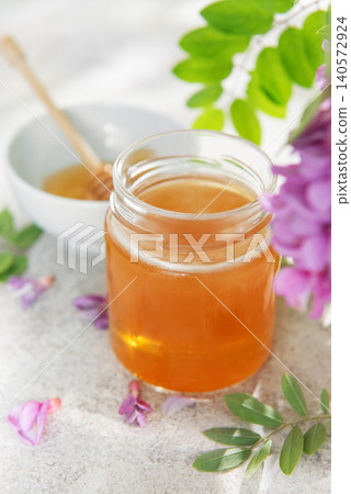Acacia honey jar with dipper and blossoms Acacia honey jar with dipper and blossoms 140572924