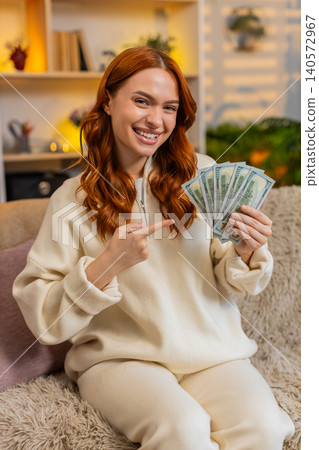 Young woman on home sofa counting cash smiling while dreaming of purchase vacation or great success Young woman on home sofa counting cash smiling while dreaming of purchase vacation or great success 140572967