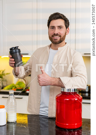 Middle-aged man mixing protein shake in kitchen smiling for fitness diet nutrition workout at home Middle-aged man mixing protein shake in kitchen smiling for fitness diet nutrition workout at home 140573007