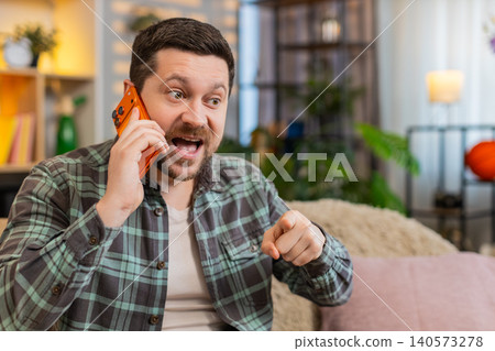 Young man on home sofa arguing on smartphone call with refusal gesture ending stressful phone talk 140573278