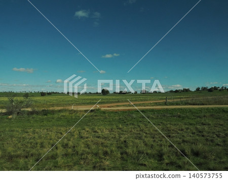 A road stretches out beyond a grassy field—a scene that evokes a sense of the vast, tranquil landscape. A road stretches out beyond a grassy field—a scene that evokes a sense of the vast, tranquil landscape. 140573755
