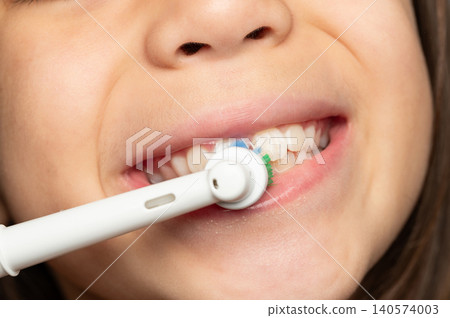 Child brushes teeth with electric toothbrush in bathroom Child brushes teeth with electric toothbrush in bathroom 140574003