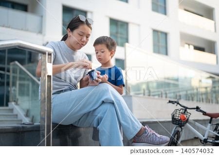 Asian woman in her 30s enjoying ice cream with her 4-year-old son outdoors Asian woman in her 30s enjoying ice cream with her 4-year-old son outdoors 140574032