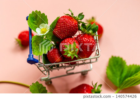 Fresh strawberries in miniature shopping cart on pink background Fresh strawberries in miniature shopping cart on pink background 140574426