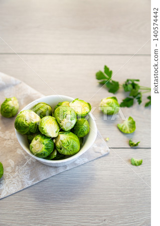 raw brussels sprouts in white bowl on wooden background raw brussels sprouts in white bowl on wooden background 140574442