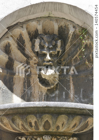 Old stone mascaron wall fountain in architectural niche Old stone mascaron wall fountain in architectural niche 140574454