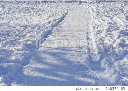 Snowy path with tire tracks and shadows Snowy path with tire tracks and shadows 140574463