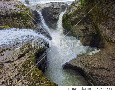 Water cascades over mossy, rugged rocks. Water cascades over mossy, rugged rocks. 140574554