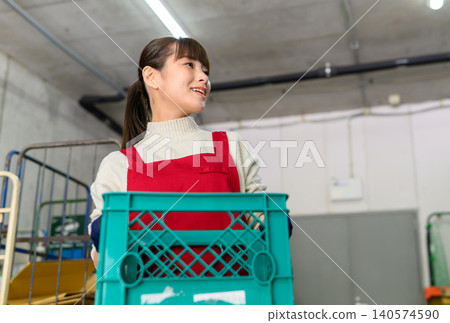 A woman holding a container in a warehouse A woman holding a container in a warehouse 140574590