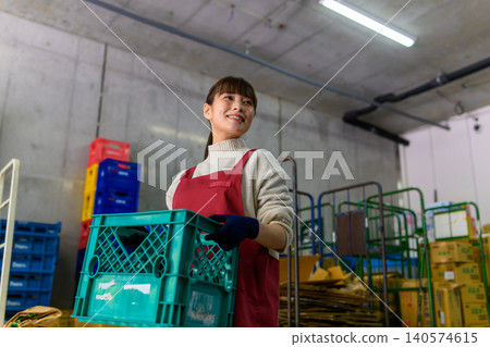 A woman holding a container in a warehouse 140574615