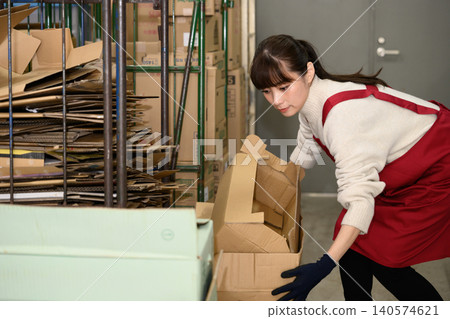 A woman carrying cardboard boxes in the back room 140574621