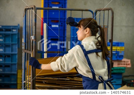 A woman pushing a cart in a warehouse A woman pushing a cart in a warehouse 140574631