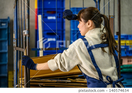 A woman pushing a cart in a warehouse A woman pushing a cart in a warehouse 140574634