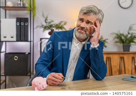Middle-aged businessman empties piggy bank counts coins plans budget after debt worries poverty fear Middle-aged businessman empties piggy bank counts coins plans budget after debt worries poverty fear 140575101