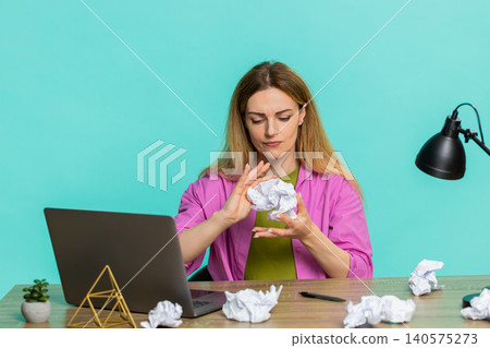 Adult woman sitting at table crumpling paper in frustration after mistake in report failed solution Adult woman sitting at table crumpling paper in frustration after mistake in report failed solution 140575273