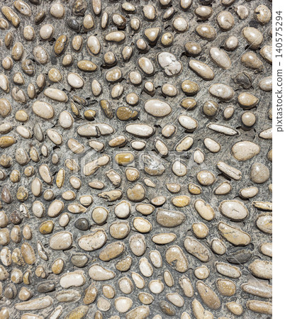 A decorative walkway made of rounded river stones in shades of brown, tan, and grey. The stones form a unique mosaic pattern and create an interesting surface. A decorative walkway made of rounded river stones in shades of brown, tan, and grey. The stones form a unique mosaic pattern and create an interesting surface. 140575294