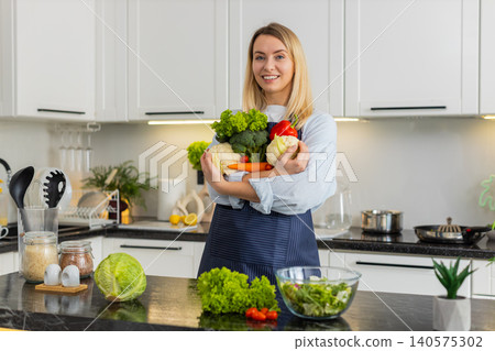 Young woman holding fresh vegetables after grocery shopping promoting keto healthy diet in kitchen Young woman holding fresh vegetables after grocery shopping promoting keto healthy diet in kitchen 140575302