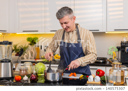 Middle-aged man smelling warm homemade soup in kitchen during healthy diet meal preparation at home Middle-aged man smelling warm homemade soup in kitchen during healthy diet meal preparation at home 140575307