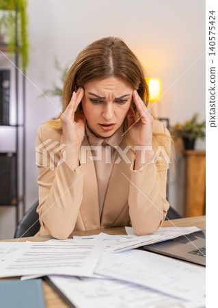 Businesswoman faces pile of bills sees costs up unhappy confused plans savings prints plan on laptop Businesswoman faces pile of bills sees costs up unhappy confused plans savings prints plan on laptop 140575424
