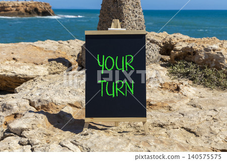 Your turn words symbol. Concept words Your turn on beautiful black blackboard. Beautiful stone blue sea blue sky background. Business your turn motivational support concept. Copy space. Your turn words symbol. Concept words Your turn on beautiful black blackboard. Beautiful stone blue sea blue sky background. Business your turn motivational support concept. Copy space. 140575575
