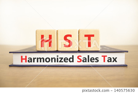 HST harmonized sales tax symbol. Concept words HST harmonized sales tax on beautiful wooden blocks and book. Beautiful white background. Business HST harmonized sales tax concept. Copy space HST harmonized sales tax symbol. Concept words HST harmonized sales tax on beautiful wooden blocks and book. Beautiful white background. Business HST harmonized sales tax concept. Copy space 140575630