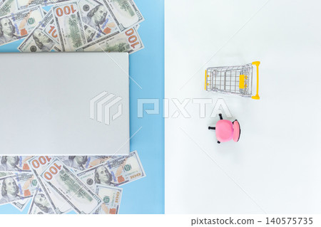 Bright cash scattered beside a tablet. Tiny shopping cart beside a pink piggy bank. Clean, minimal background. Ideal for finance, savings, or shopping concepts. Simple, cheerful, modern aesthetic 140575735