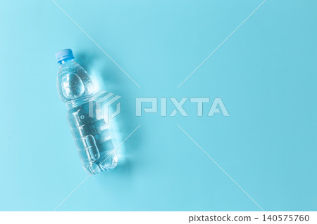 Clear water bottle rests on soft blue background. Minimalist composition draws attention to clean design. Cool tones evoke freshness and simplicity. Ideal for health, hydration Clear water bottle rests on soft blue background. Minimalist composition draws attention to clean design. Cool tones evoke freshness and simplicity. Ideal for health, hydration 140575760