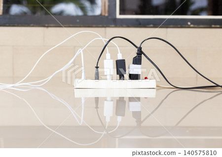 Close-up of an overloaded power strip with multiple plugs and tangled wires, representing electrical fire hazards and domestic safety risks Close-up of an overloaded power strip with multiple plugs and tangled wires, representing electrical fire hazards and domestic safety risks 140575810