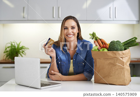 Happy woman, laptop and credit card with grocery bag for payment, online shopping or order in kitchen at home. Portrait of female person with smile, computer or debit in purchase or delivery at house 140575909