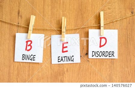 BED binge eating disorder symbol. Concept words BED binge eating disorder on beautiful white papers on clothespins. Beautiful wooden background. Medical BED binge eating disorder concept. Copy space. BED binge eating disorder symbol. Concept words BED binge eating disorder on beautiful white papers on clothespins. Beautiful wooden background. Medical BED binge eating disorder concept. Copy space. 140576027