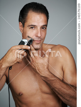 Man, portrait and electric razor for beard maintenance with confidence for grooming, trimmer or grey background. Male person, face and hair removal shaving in studio for skincare, hygiene or mockup Man, portrait and electric razor for beard maintenance with confidence for grooming, trimmer or grey background. Male person, face and hair removal shaving in studio for skincare, hygiene or mockup 140576109