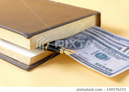 A hardcover notebook with pen tucked between pages like bookmark and bank note. 140576233
