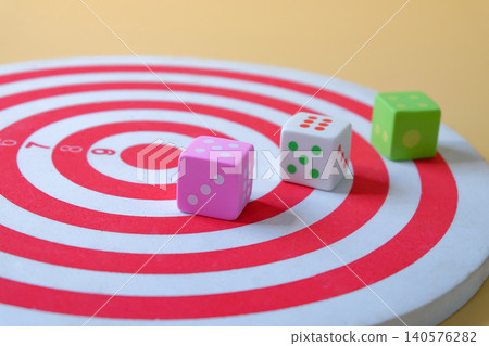 Colorful dice on red dartboard and playful design. Colorful dice on red dartboard and playful design. 140576282