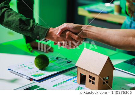 Business handshake over property papers and charts with a small house model on a desk, showing a real estate deal, home loan approval, or partnership in a modern office. Business handshake over property papers and charts with a small house model on a desk, showing a real estate deal, home loan approval, or partnership in a modern office. 140576366