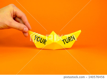 Your turn words symbol. Concept words Your turn on beautiful yellow paper boat. Beautiful orange background. Businessman hand. Business your turn motivational support concept. Copy space. Your turn words symbol. Concept words Your turn on beautiful yellow paper boat. Beautiful orange background. Businessman hand. Business your turn motivational support concept. Copy space. 140576456