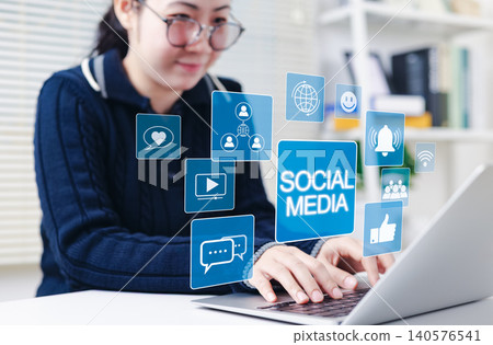 Social media networking and communication concept. Woman using laptop with social media icons, chat, likes, notifications, video, representing digital networking, engagement, and online interaction. 140576541