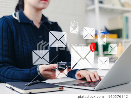 Email notification and communication concept. Woman using laptop and smartphone with email icons, new message notifications, symbolizing digital communication, online messaging, and email marketing. 140576542