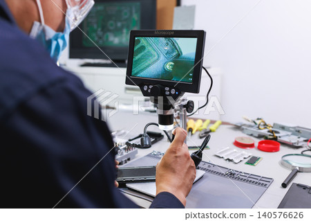 Technician using a digital microscope to inspect a circuit board in an electronics repair workspace, showing precision work, testing, and modern technology. Technician using a digital microscope to inspect a circuit board in an electronics repair workspace, showing precision work, testing, and modern technology. 140576626