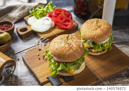 Two savory delicious homemade cheeseburger in kitchen gadget modern air fryer on wooden background. Lifestyle trendy of new cooking. Two savory delicious homemade cheeseburger in kitchen gadget modern air fryer on wooden background. Lifestyle trendy of new cooking. 140576872