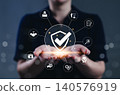 Work safety and compliance management concept. A person holds a shield check surrounded by safety, compliance, and risk assessment symbols, representing occupational health and workplace regulations. 140576919