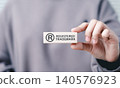 Registered trademark, intellectual property concept. A person holds wooden block the registered trademark symbol and text, representing intellectual property, copyright, patent, and brand protection. 140576923