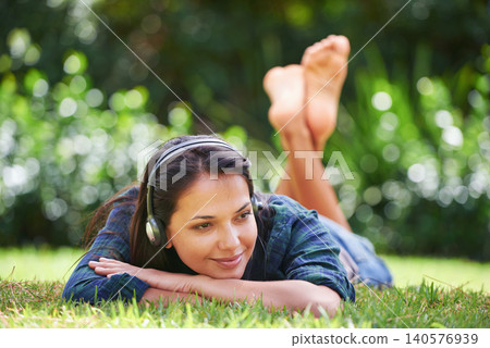 Grass, thinking and woman with headphones, relax and streaming music with peace, sound and sunshine. Person in a park, outdoor and girl with headset and podcast with radio and weekend break in garden Grass, thinking and woman with headphones, relax and streaming music with peace, sound and sunshine. Person in a park, outdoor and girl with headset and podcast with radio and weekend break in garden 140576939