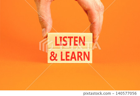 Listen and learn words symbol. Concept words Listen and learn on beautiful wooden blocks. Beautiful orange background. Businessman hand. Business listen and learn support concept. Copy space. 140577056