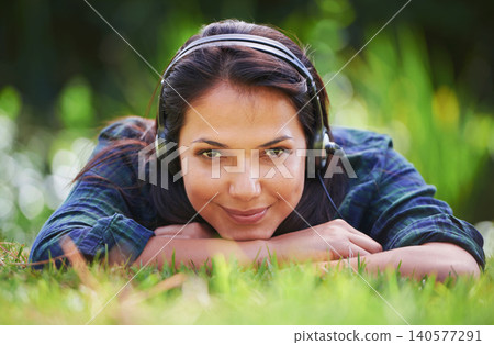 Grass, portrait and woman with headphones, park and streaming audio with peace, sound and sunshine. Person, outdoor and girl with headset, summer or podcast with radio, relaxing or listening to music Grass, portrait and woman with headphones, park and streaming audio with peace, sound and sunshine. Person, outdoor and girl with headset, summer or podcast with radio, relaxing or listening to music 140577291